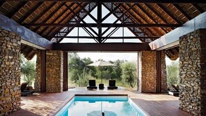 Een zwembadgedeelte met stenen muren, een houten terras en uitzicht op bomen.
