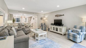 A spacious living room with a sofa, armchairs, a coffee table, and a television. - Sunset Rentals | Greens 170 Dog Friendly! (Hilton Head Island)