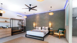 A modern bedroom with a bed, a ceiling fan, a wardrobe, a chair, and a bedside table. - Lula Boutique by The Studios Ubud  (Ubud)