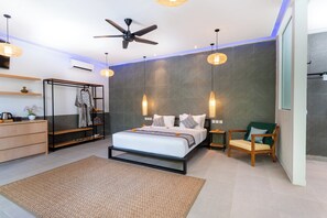 Une chambre moderne comprenant un lit, un ventilateur de plafond, une armoire, une chaise et une table de chevet.