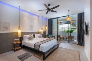 A modern bedroom with a bed, bedside tables, a ceiling fan, and a view of a balcony with chairs and a plant. - Lula Boutique by The Studios Ubud  (Ubud)