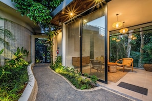 A modern outdoor area with a pathway leading to a seating area with wicker furniture. - Lula Boutique by The Studios Ubud (Ubud)