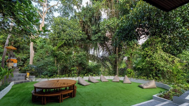 A garden with a wooden table and beige cushions.