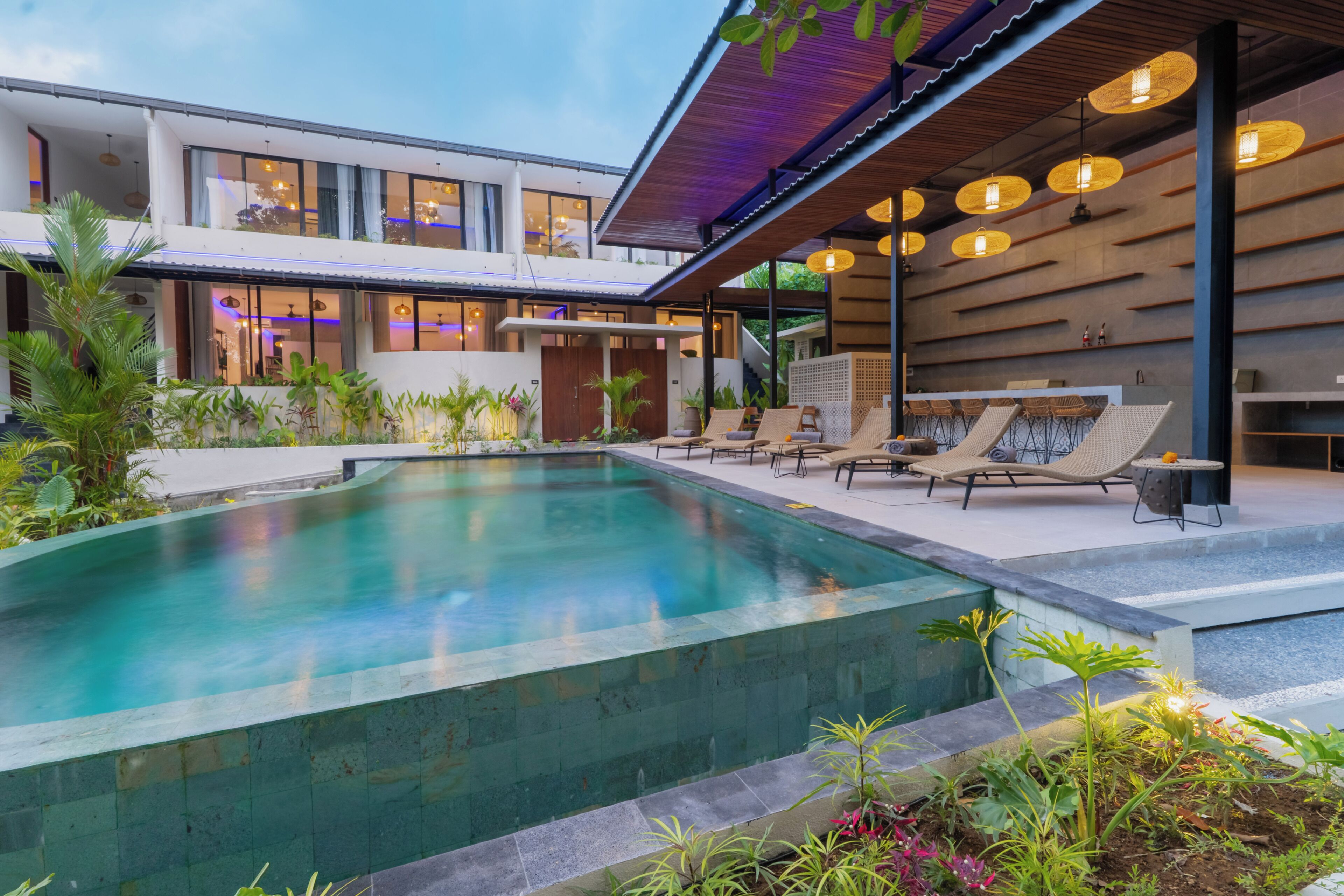 A modern outdoor pool area with lounge chairs and a covered seating area.