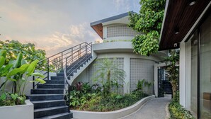 A modern building with a staircase leading to a balcony, surrounded by lush greenery. - Lula Boutique by The Studios Ubud  (Ubud)