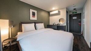A hotel room with a bed, bedside table, lamp, and a mirror on the wall. - Hotel Parkview (Seoul)