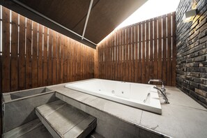 A modern spa area with a large rectangular bathtub, a stone bench, and a wooden wall with vertical slats. - Hotel Parkview (Seoul)
