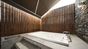 A spa area with a large bathtub, a stone bench, and a brick wall. - Hotel Parkview (Seoul)
