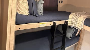 A bunk bed with a ladder, a headboard, and a blanket.
