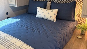 A bedroom with a bed, a nightstand, a wall unit with storage, and a patterned wall. - Waterfront Getaway with Campfire Fishing Kayaking Biking Near Beaches & MS (Coden)