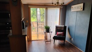 Une cuisine avec une porte-fenêtre coulissante donnant sur un espace extérieur, une chaise avec une couverture et un panneau accroché au mur.
