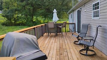 A wooden deck with outdoor furniture, including a table and chairs, and a barbecue grill.