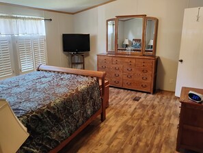 A bedroom with a bed, dresser, television, and a mirror.