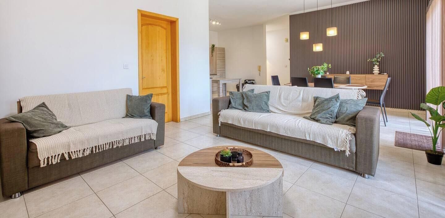 Ein Wohnzimmer mit zwei Sofas, einem Couchtisch und einem Essbereich mit Tisch und Stühlen.