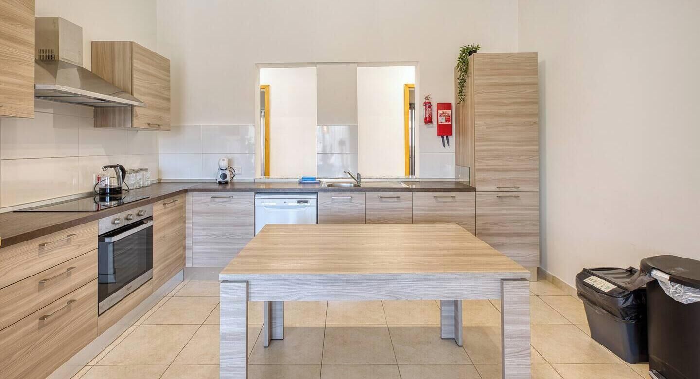 A modern kitchen with a central island, built-in oven, and stainless steel appliances.