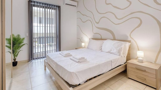 Une chambre d’hôtel avec un lit, une table de chevet, une lampe et une plante en pot.