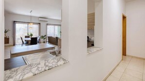 Un intérieur moderne comprenant un coin repas, une cuisine et un couloir menant à une porte.