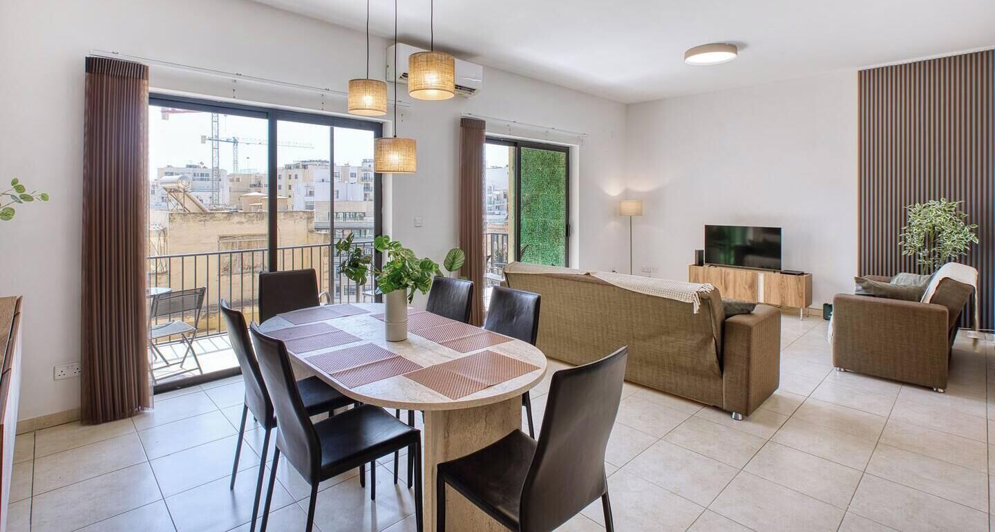 A modern living room with a dining area, large windows, and a balcony.
