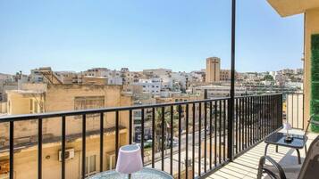 A balcony with a table, a chair, and a view of a cityscape.