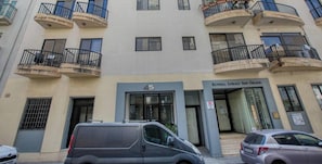 A multi-story building with balconies, a ground-level entrance, and a sign indicating the name 'Kunsill Lokali San Gilian.' - Spinola Bay 3BR w/ beautiful Sunny Balcony & AC (San Ġiljan)