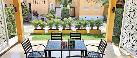 An outdoor patio with a table and chairs, surrounded by potted plants and a view of buildings.