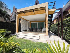 A modern building with a covered patio, outdoor seating, and a staircase.
