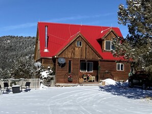 Eine Holzhütte mit rotem Dach, einer Satellitenschüssel und einem schneebedeckten Hof.