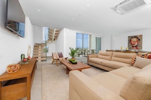 Ein modernes Wohnzimmer mit einer Couch, einem Couchtisch und einer Treppe zu einer oberen Etage.