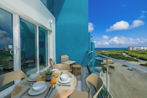 Ein Balkon mit Esstisch für zwei Personen, mit Blick auf Strand und Meer.