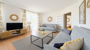 A modern living room with a flat-screen TV, a grey sofa, a coffee table, and a striped curtain. - Apartamenty Sun & Snow Wybrzeże II (Dziwnów)