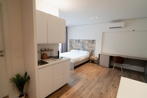 A modern bedroom with a bed, bedside table, and a small desk area. - Charming Catania Apartment With Private Entrance and Balcony (Catania)