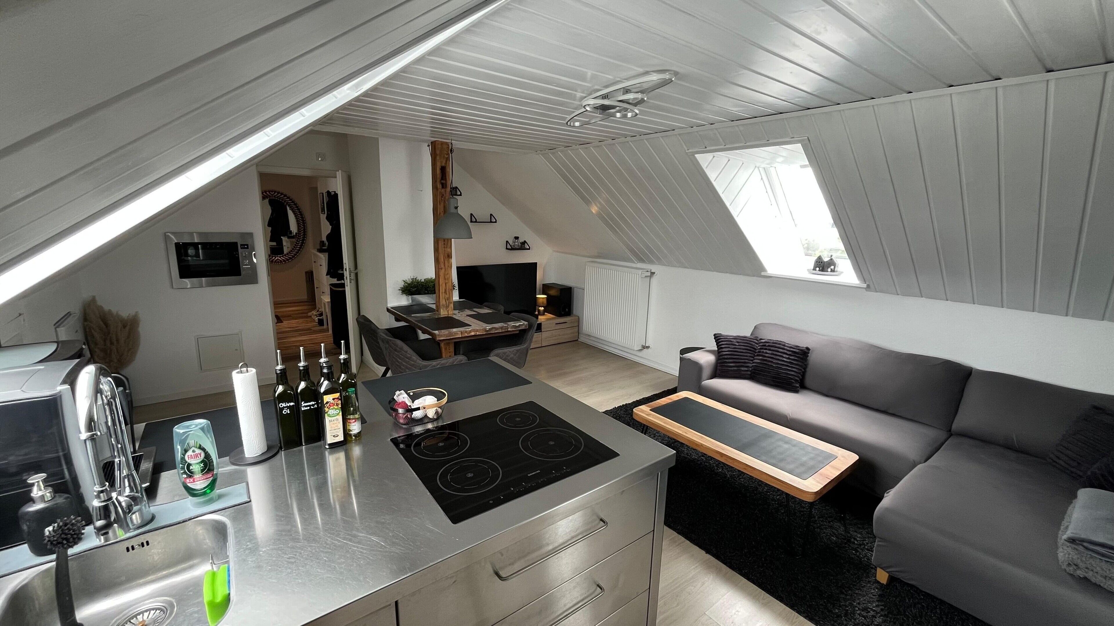 A compact kitchen with a dining area and a living space, featuring a skylight and a built-in stove.