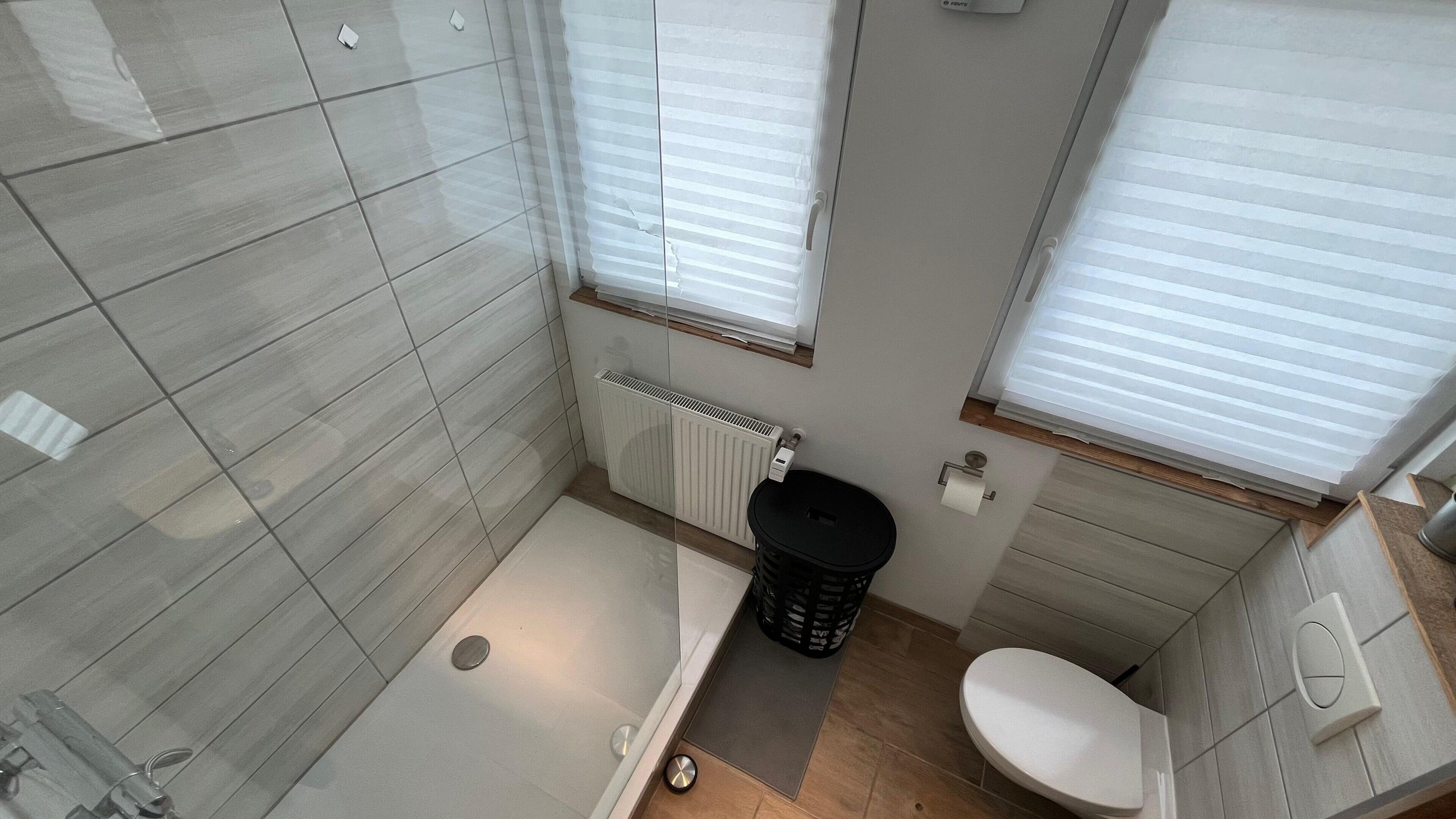 Ein Badezimmer mit Dusche, Toilette und Handtuchheizung.
