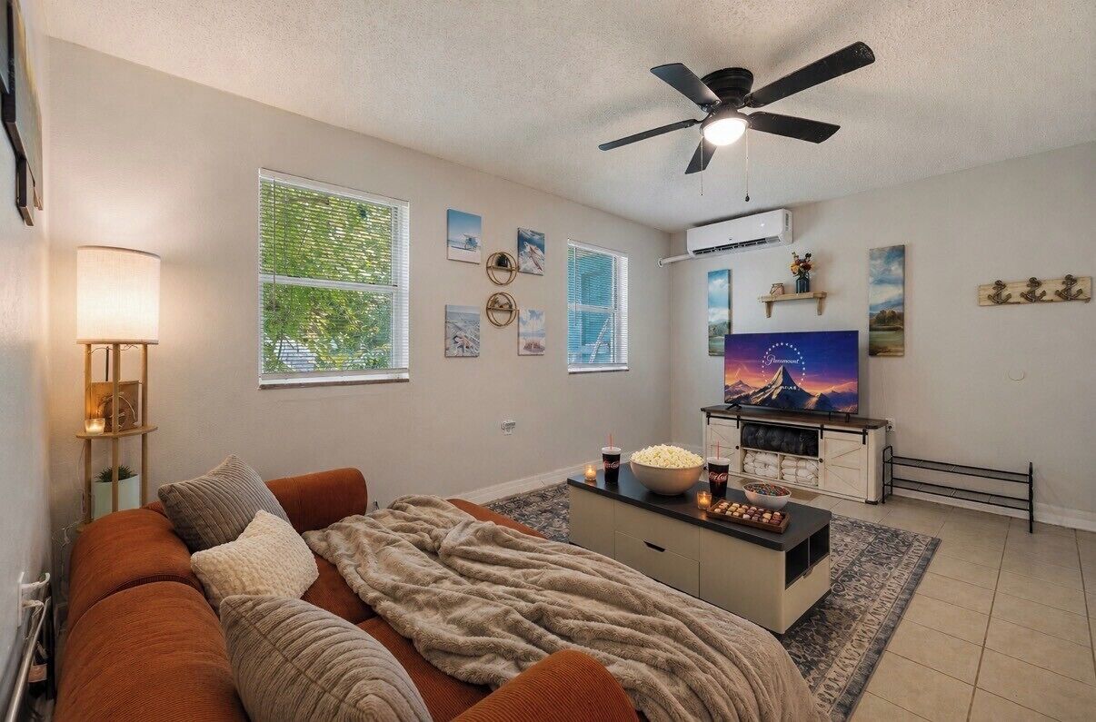 A living room with a sofa, a coffee table, a TV, and a ceiling fan.