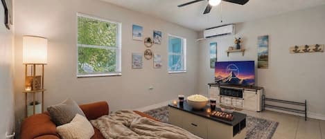 A living room with a sofa, a coffee table, a TV, and a ceiling fan.
