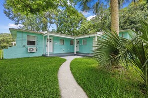 A two-story house with a pathway leading to the front door. - Sleep 4 in this bright Pensacola cottage just minutes from Perdido Key's white sands and the National Naval Aviation Museum. Full kitchen, in-unit laundry, comfy queen bed, and a picnic-table yard. Your easy Gulf Coast home base awaits! (Pensacola)