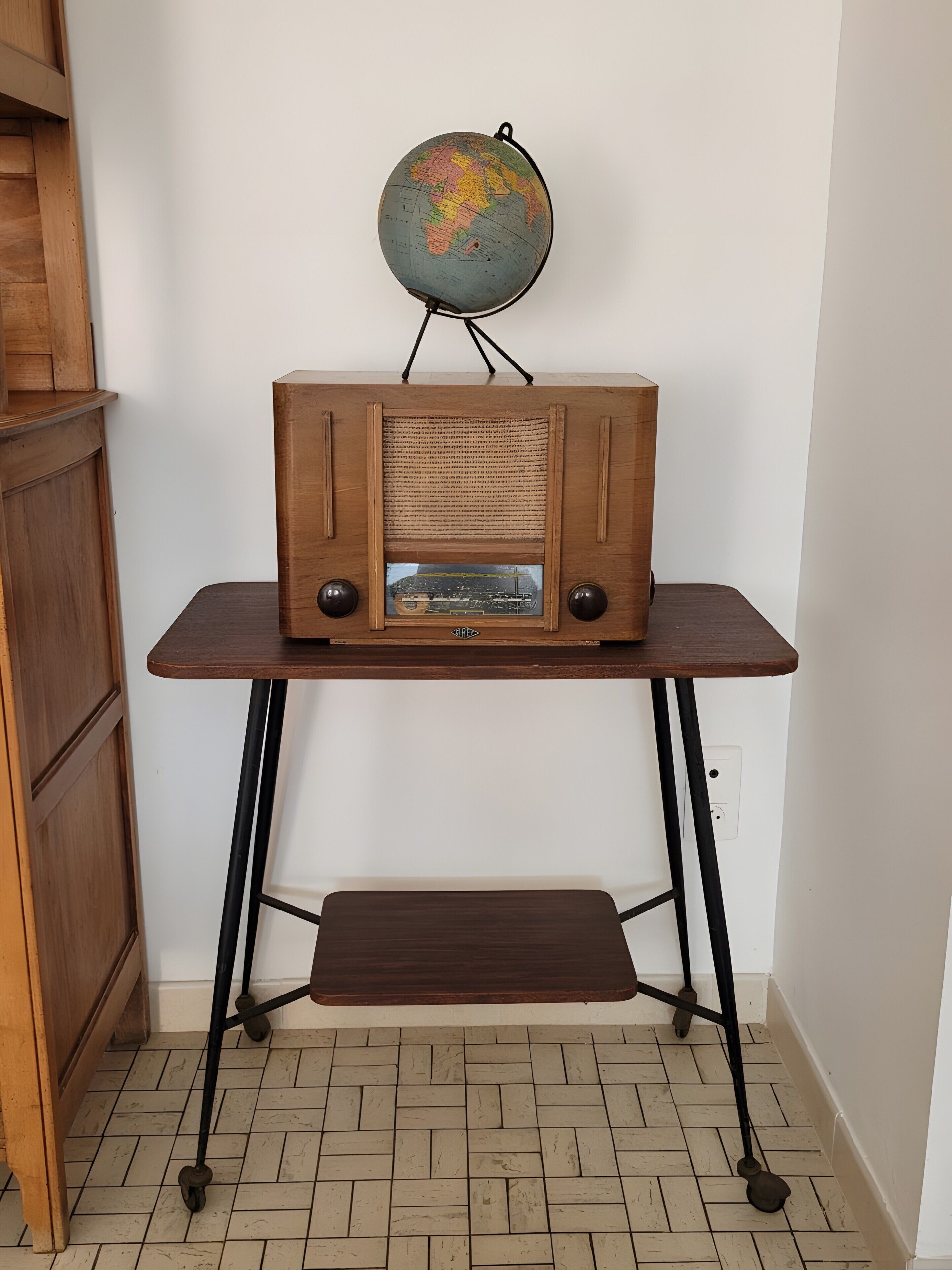 A wooden radio on a table with a globe above it.