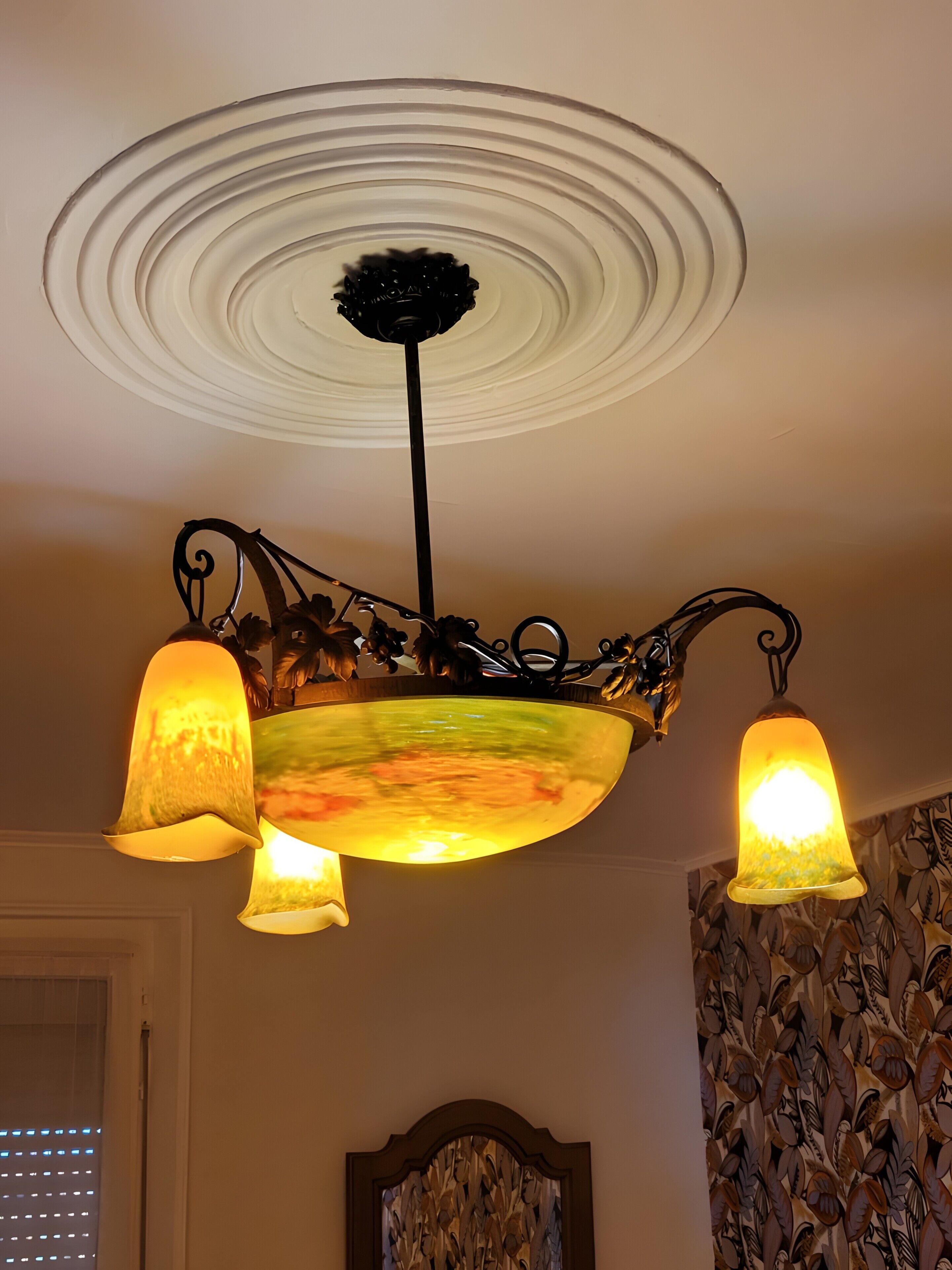 Eine Decke mit einer verzierten Leuchte, die drei Lampen umfasst.