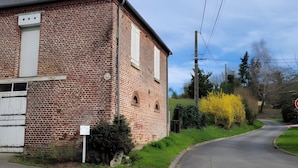 Um edifício de tijolos com porta e janelas brancas, uma estrada sinuosa e um sinalizador.