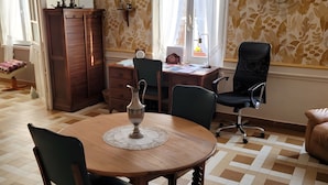 Uma sala de jantar com uma mesa de madeira, cadeiras, um candelabro e papel de parede estampado.