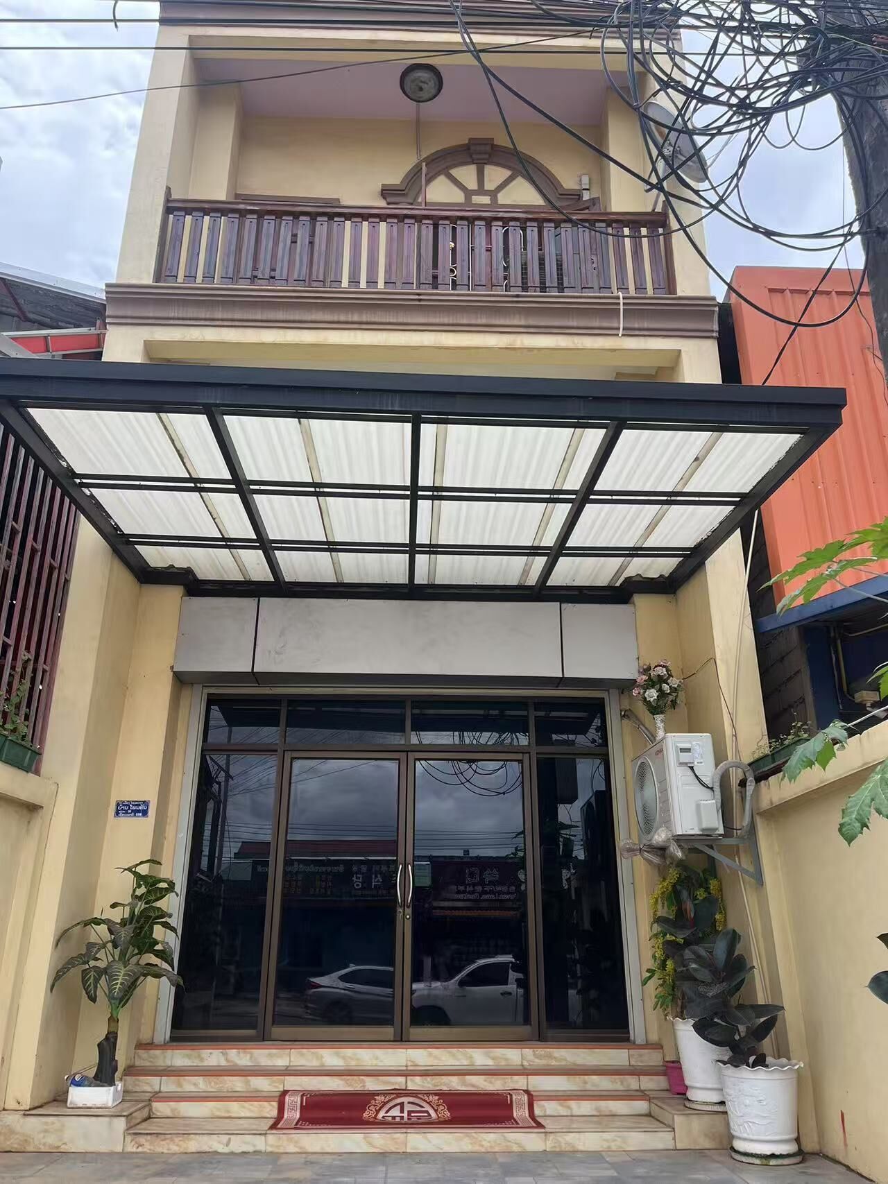 A two-story building with a covered entrance and a balcony.