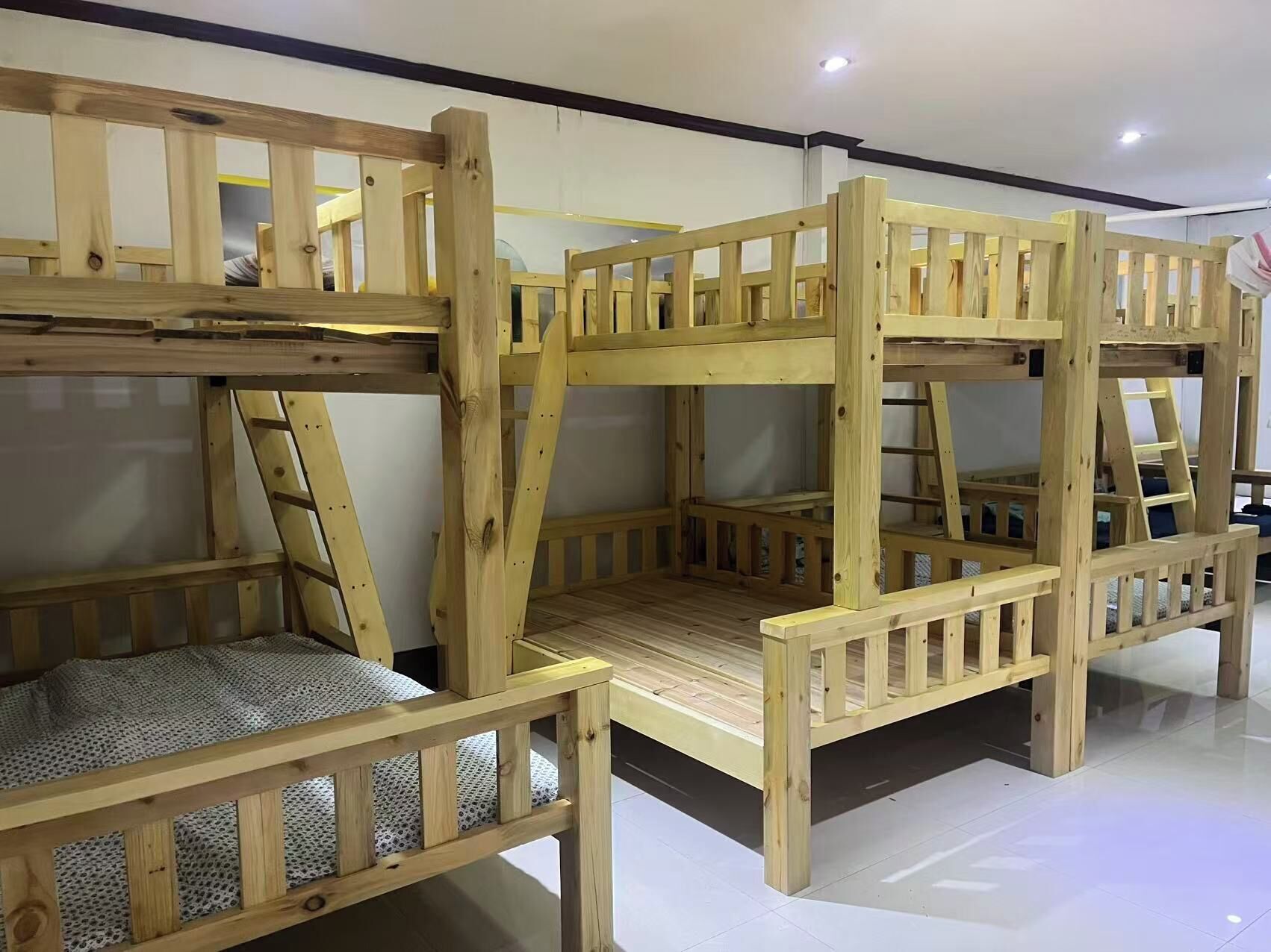 A bunk bed with a ladder and a small table, wooden railings, and a patterned cushion.