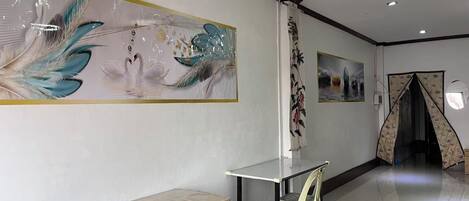 A spacious room with a long table, a chair, and a wall-mounted shelf.
