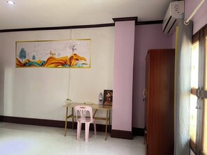 A room with a dining table, a pink chair, a painting on the wall, and an air conditioning unit. - Charming 8-bedroom bed & breakfast with AC in Vientiane Capital (Vientiane)