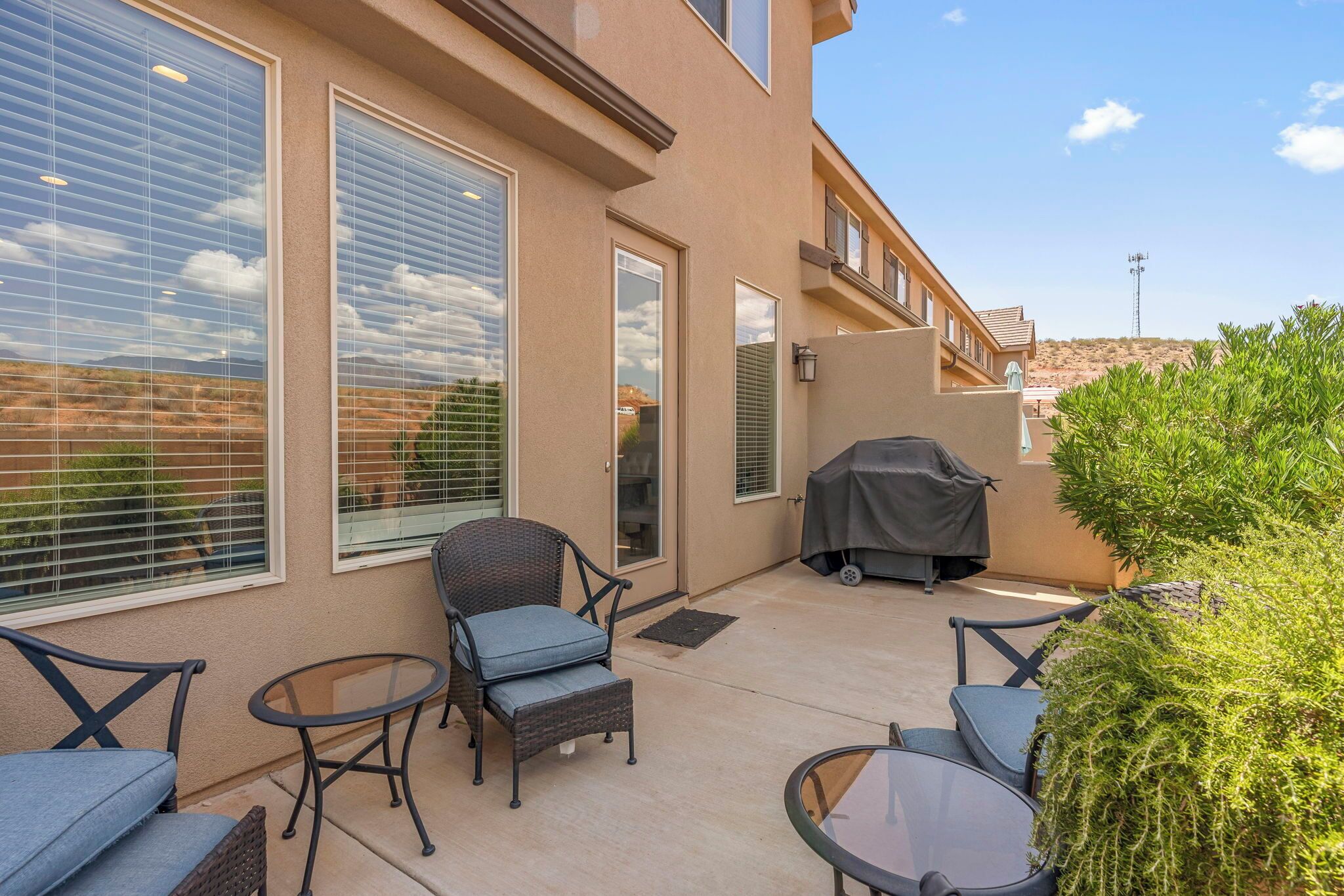 A patio area with outdoor furniture, a barbecue grill, and a view of the surrounding landscape.