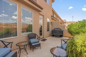Un espace patio aménagé avec du mobilier d’extérieur, un barbecue et une vue sur le paysage environnant.