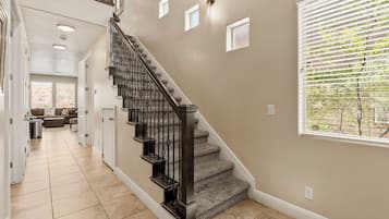 A staircase with a handrail, carpeted steps, and a wall with a window and small square lights.