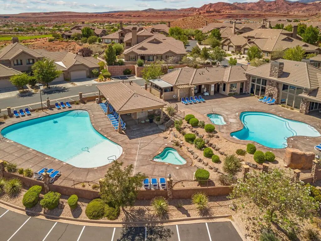 Een resort met diverse zwembaden, ontspanningsruimtes en een woestijnlandschap op de achtergrond.