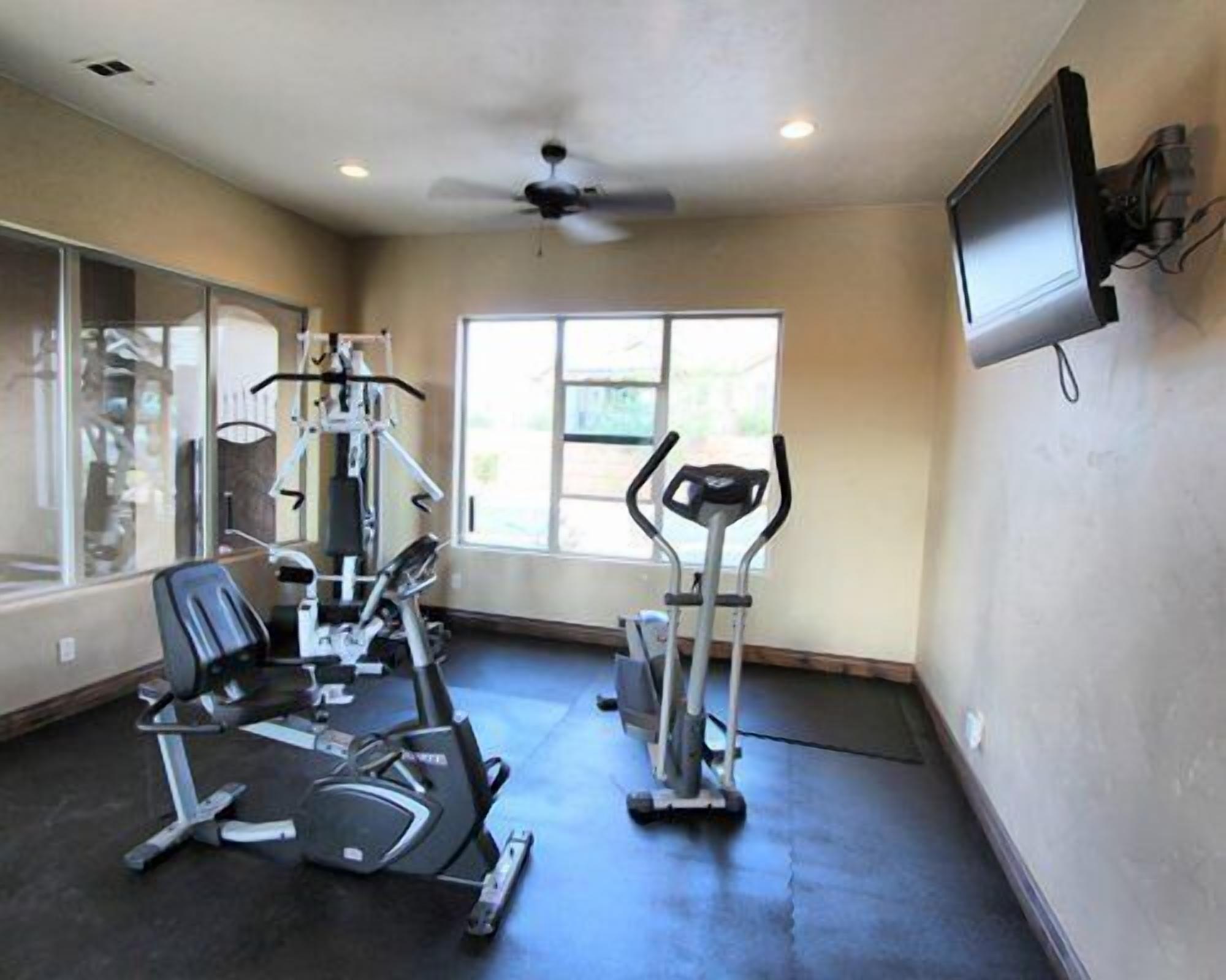 A gym with cardio machines, a television, and a large window.
