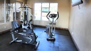 Et fitnessrum med træningsmaskiner, fjernsyn og et stort vindue.